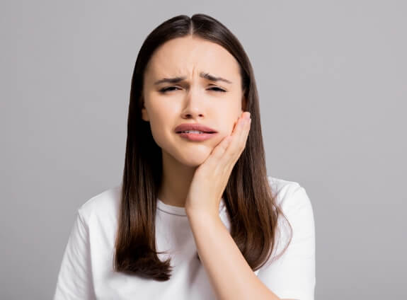 Woman wincing and holding her cheek in pain