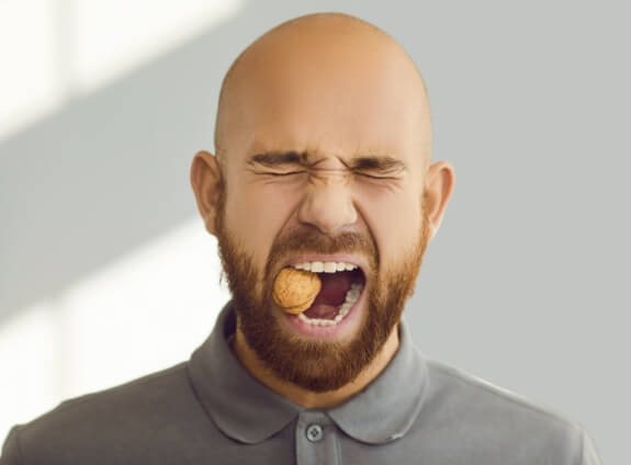 Man crunching a walnut with his teeth