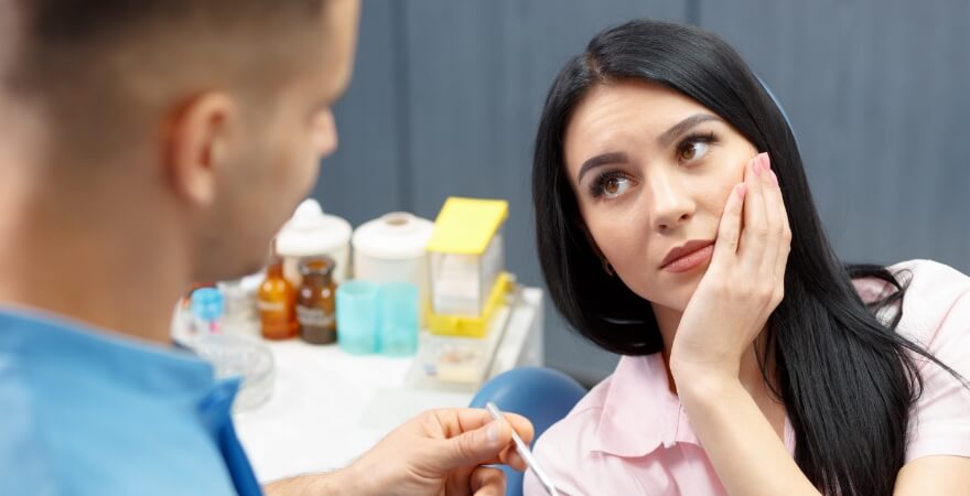 Woman holding her cheek in pain needing root canal retreatment